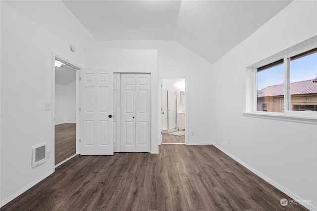 unfurnished bedroom with ensuite bathroom, dark hardwood / wood-style flooring, lofted ceiling, and a closet