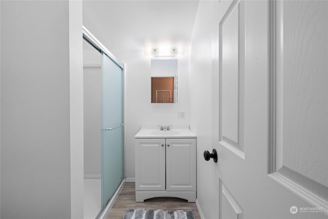 bathroom featuring hardwood / wood-style flooring, vanity, and a shower with shower door