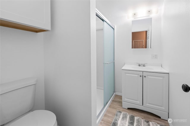 bathroom featuring hardwood / wood-style floors, vanity, a shower with door, and toilet