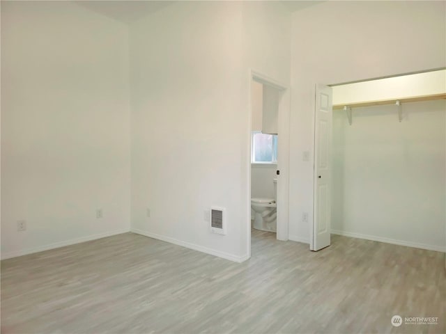 unfurnished bedroom featuring light wood-type flooring and ensuite bath