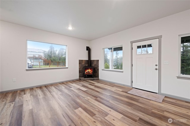 unfurnished living room featuring light wood-type flooring and a wood stove