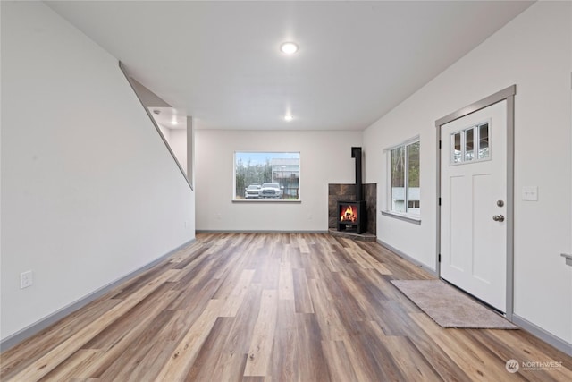 unfurnished living room featuring a wood stove, hardwood / wood-style floors, and a healthy amount of sunlight