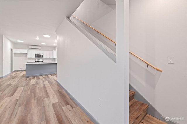 stairway with hardwood / wood-style flooring and an AC wall unit