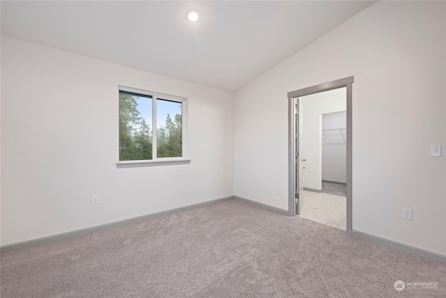 carpeted empty room featuring lofted ceiling