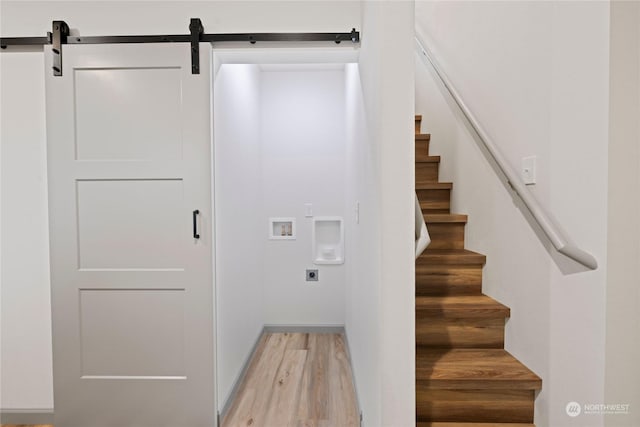 stairway featuring a barn door and hardwood / wood-style flooring