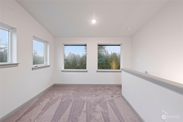 unfurnished room with light colored carpet and vaulted ceiling