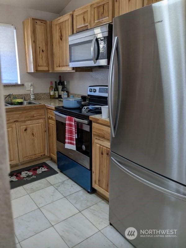 kitchen featuring light tile patterned flooring, stainless steel appliances, vaulted ceiling, and sink