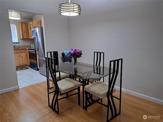 dining space featuring lofted ceiling and light hardwood / wood-style flooring