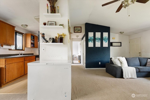 kitchen featuring ceiling fan, sink, light colored carpet, and lofted ceiling