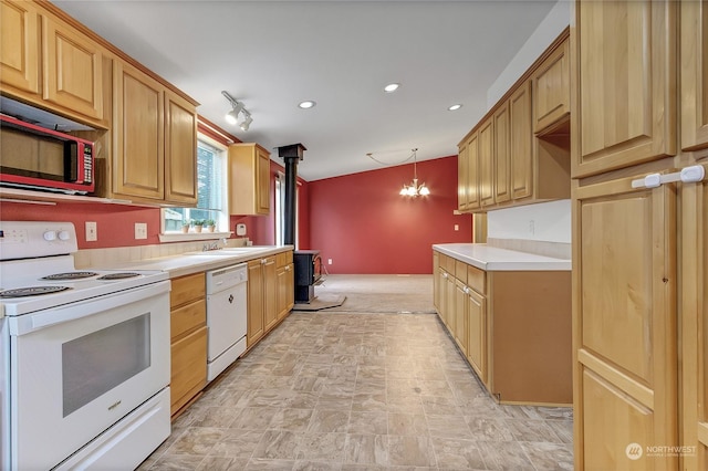 kitchen with an inviting chandelier, a wood stove, white appliances, rail lighting, and pendant lighting