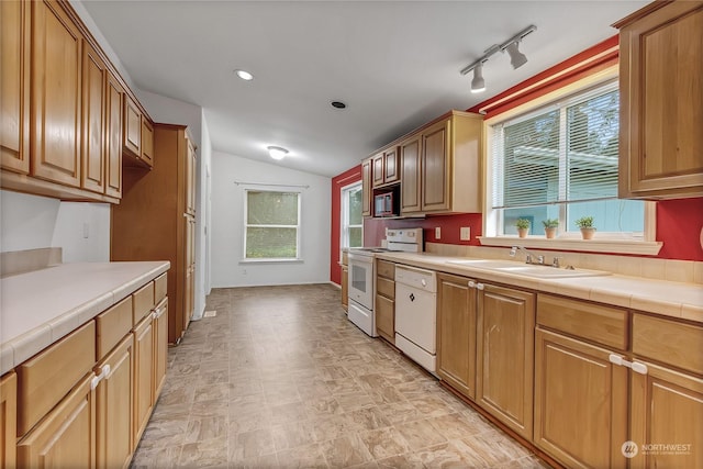 kitchen with white appliances, vaulted ceiling, tile counters, track lighting, and sink