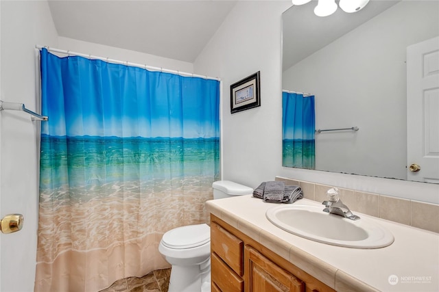 bathroom featuring lofted ceiling, vanity, and toilet