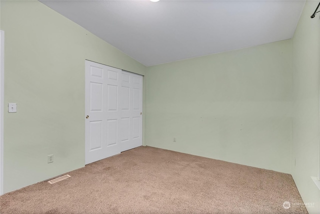 unfurnished bedroom featuring lofted ceiling, a closet, and carpet