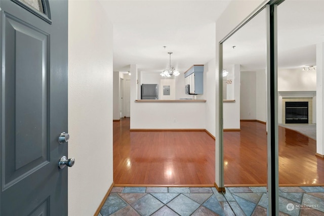 entrance foyer featuring a tile fireplace, wood-type flooring, and an inviting chandelier