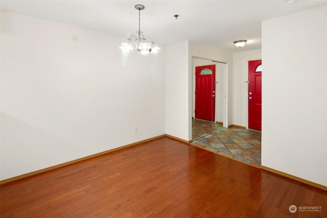 unfurnished room with hardwood / wood-style floors and an inviting chandelier