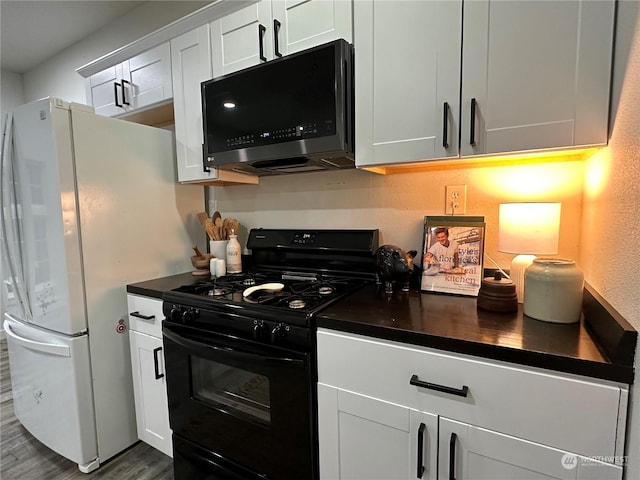 kitchen with dark hardwood / wood-style flooring, white cabinets, black gas range oven, and white refrigerator