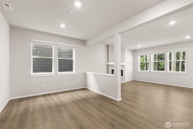 unfurnished room with a glass covered fireplace, recessed lighting, wood finished floors, and visible vents