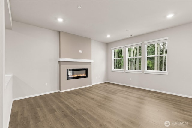 unfurnished living room with recessed lighting, baseboards, and wood finished floors