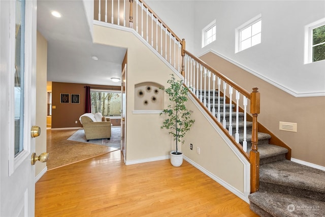 stairway with a towering ceiling and hardwood / wood-style flooring