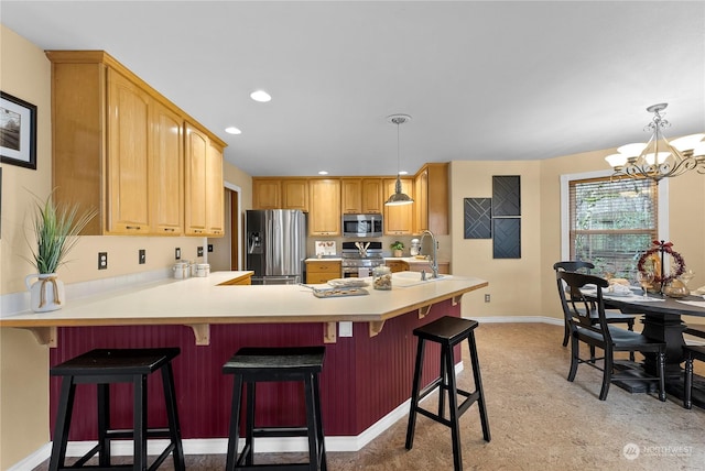 kitchen with sink, a kitchen bar, stainless steel appliances, and a chandelier