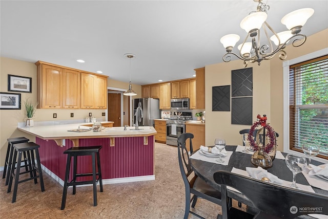 kitchen with pendant lighting, an inviting chandelier, a breakfast bar area, kitchen peninsula, and stainless steel appliances