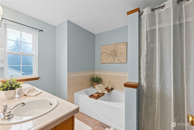 bathroom featuring a washtub, vanity, tile walls, and hardwood / wood-style flooring