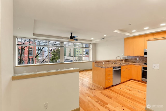 kitchen featuring ceiling fan, sink, light brown cabinets, kitchen peninsula, and a tray ceiling