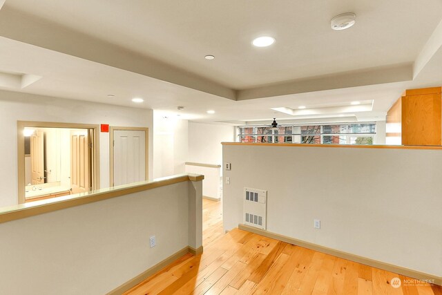 spare room with a raised ceiling and light hardwood / wood-style flooring