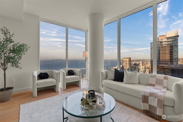 living room with a wall of windows, a water view, and hardwood / wood-style flooring