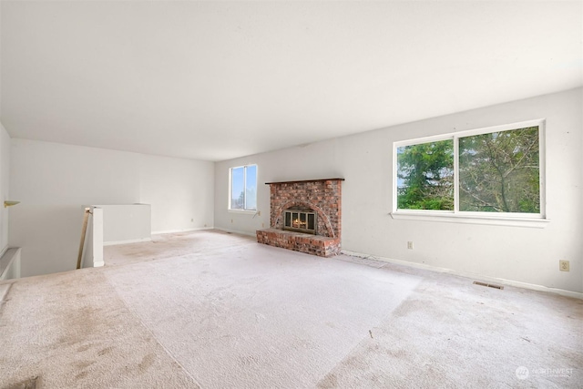 unfurnished living room featuring a fireplace, carpet, and a healthy amount of sunlight