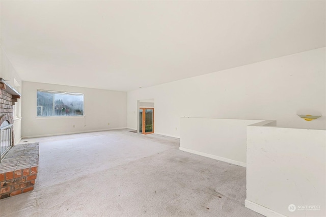 unfurnished living room with light carpet and a brick fireplace