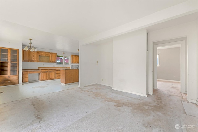 unfurnished living room with sink and an inviting chandelier