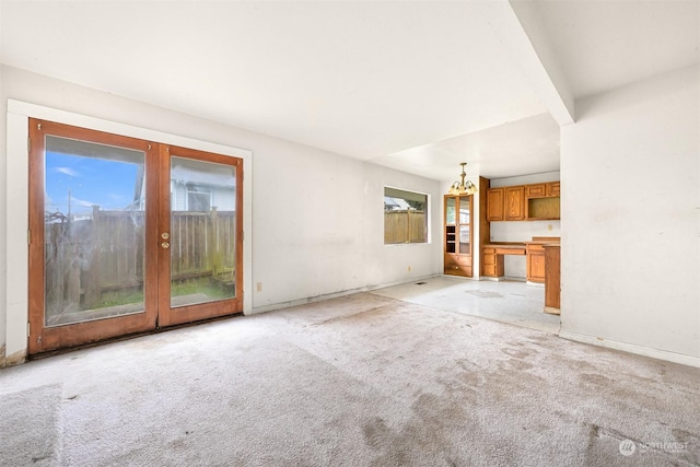 unfurnished living room with french doors, light colored carpet, and a wealth of natural light