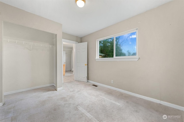 unfurnished bedroom featuring light carpet and a closet