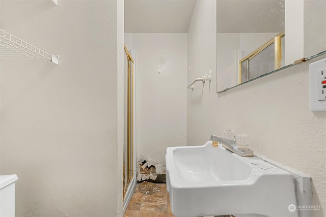 bathroom featuring sink, an enclosed shower, and toilet