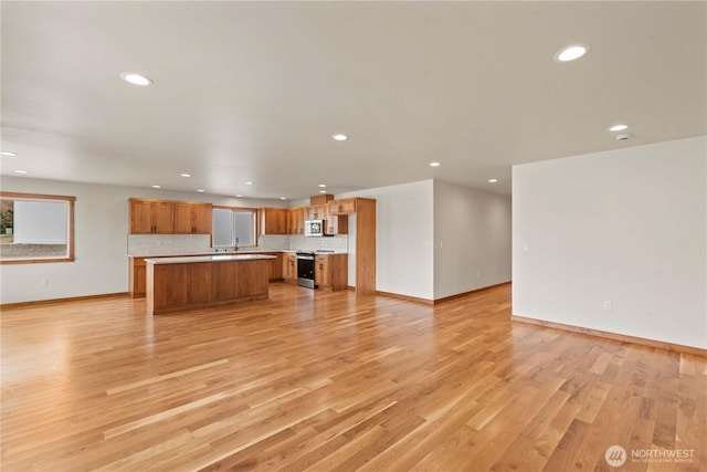 898 N Nile Ave, East Wenatchee, WA 98802 - unfurnished living room with recessed lighting, baseboards, light wood finished floors, and a sink