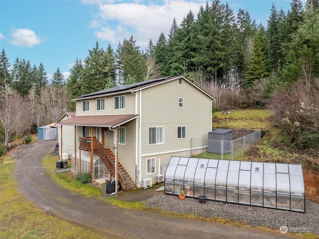 exterior space with central AC unit, an outbuilding, and solar panels