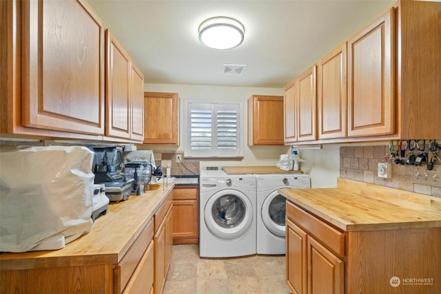 clothes washing area with cabinets and washing machine and clothes dryer