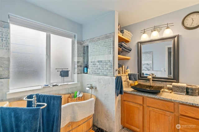 bathroom with vanity, a healthy amount of sunlight, and tiled shower