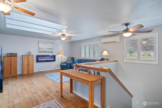 interior space with a wall unit AC, a healthy amount of sunlight, a skylight, and light hardwood / wood-style flooring