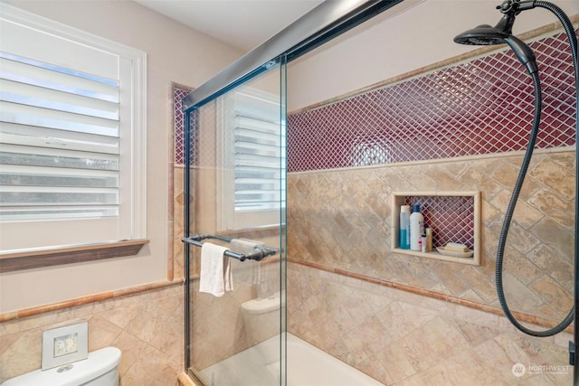 bathroom with tile walls, an enclosed shower, and toilet