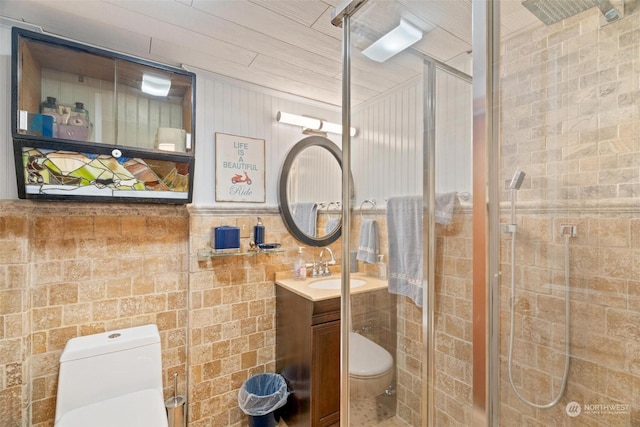 bathroom featuring a shower with door, vanity, and toilet