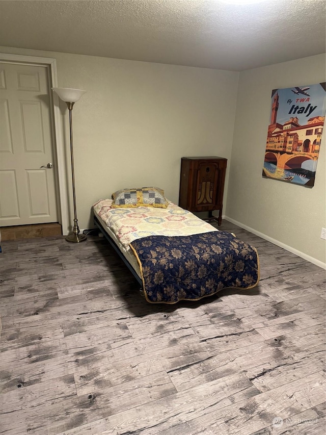 bedroom featuring wood-type flooring and a textured ceiling