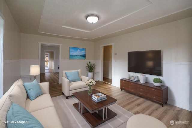 living room with light wood-type flooring and a tray ceiling