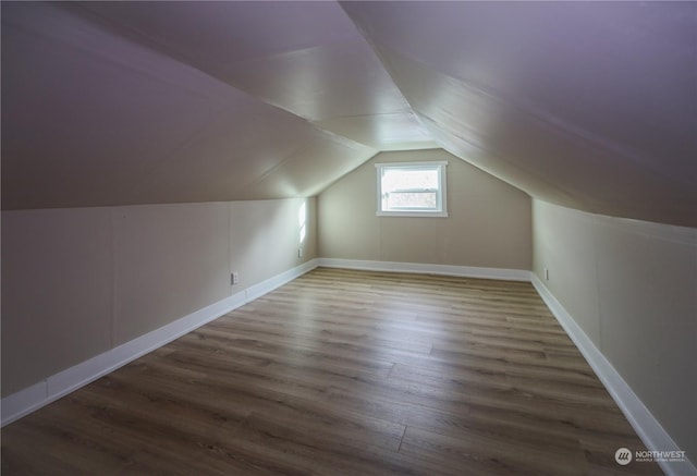 additional living space with vaulted ceiling and dark wood-type flooring