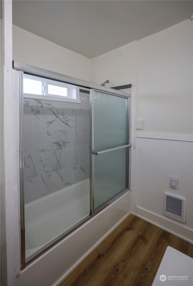 bathroom featuring wood-type flooring and enclosed tub / shower combo