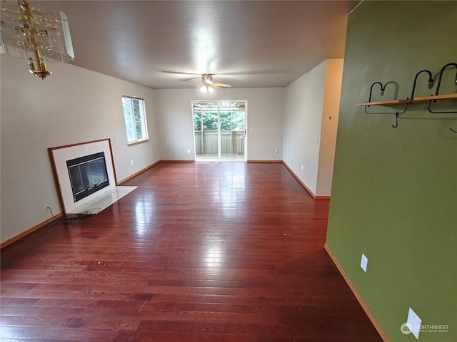 unfurnished living room featuring a tiled fireplace, ceiling fan, and wood-type flooring