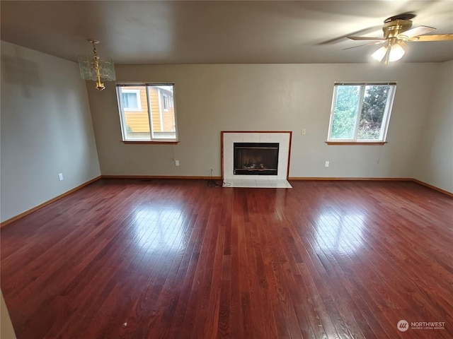 unfurnished living room with a fireplace, dark hardwood / wood-style flooring, and ceiling fan with notable chandelier