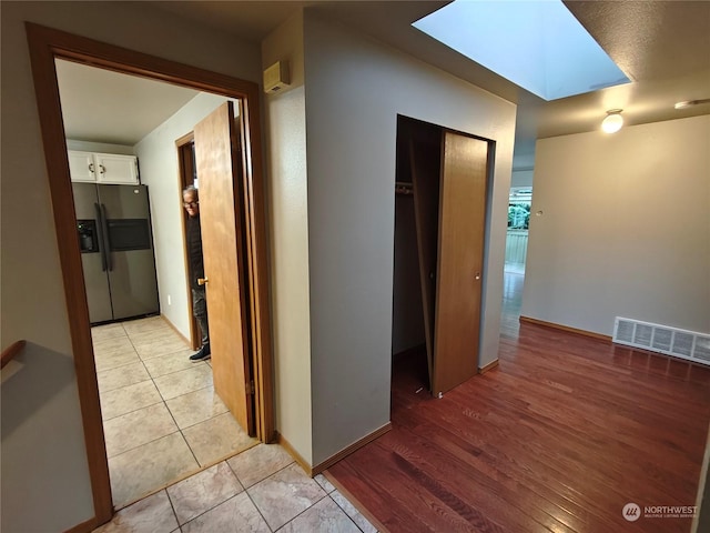 hallway with a skylight and light tile patterned floors