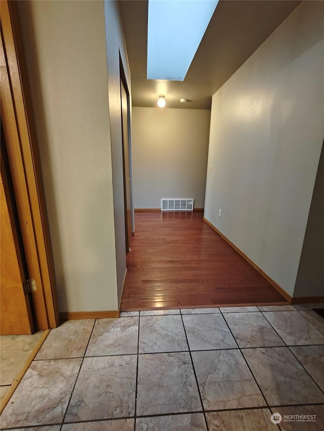 hall with light hardwood / wood-style flooring and a skylight